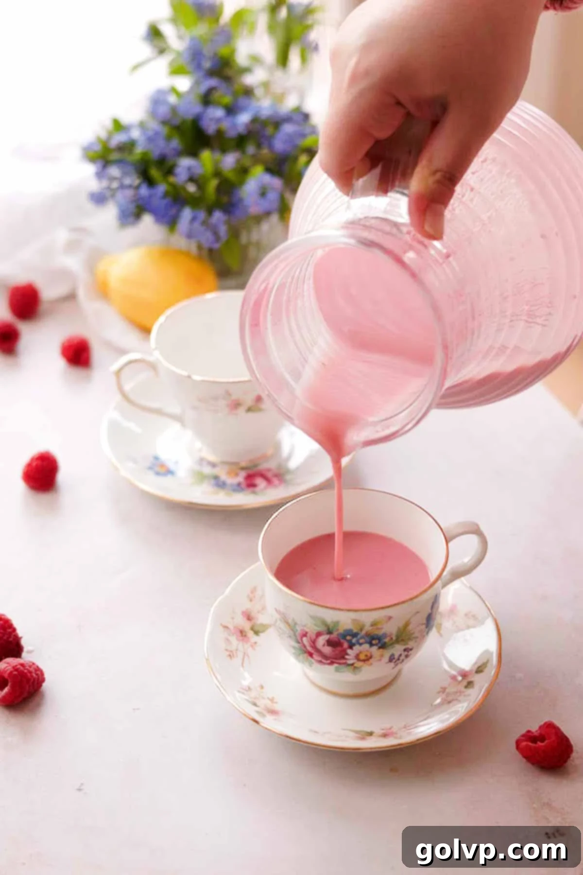 pouring raspberry posset out of the pitcher and into teacups on saucers