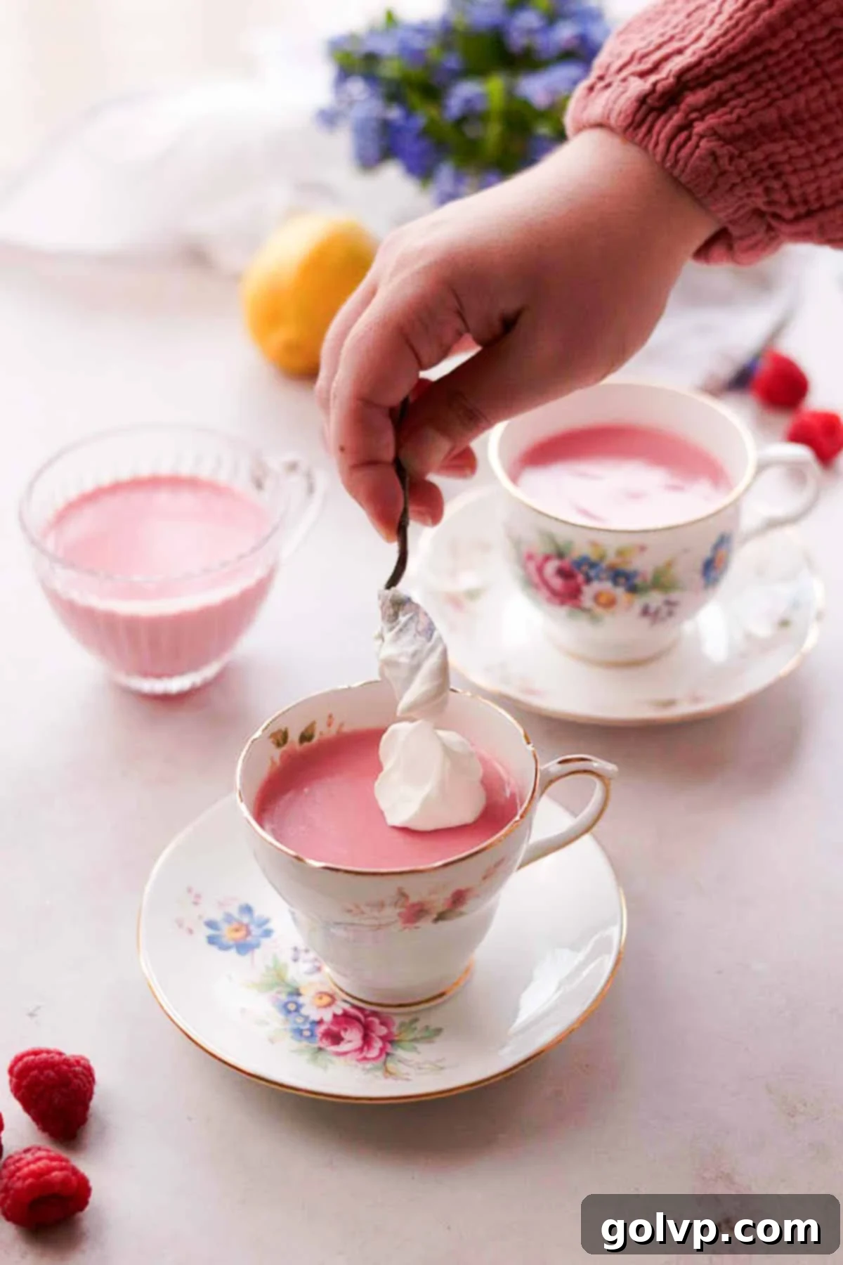 adding dollops of whipped cream onto raspberry posset