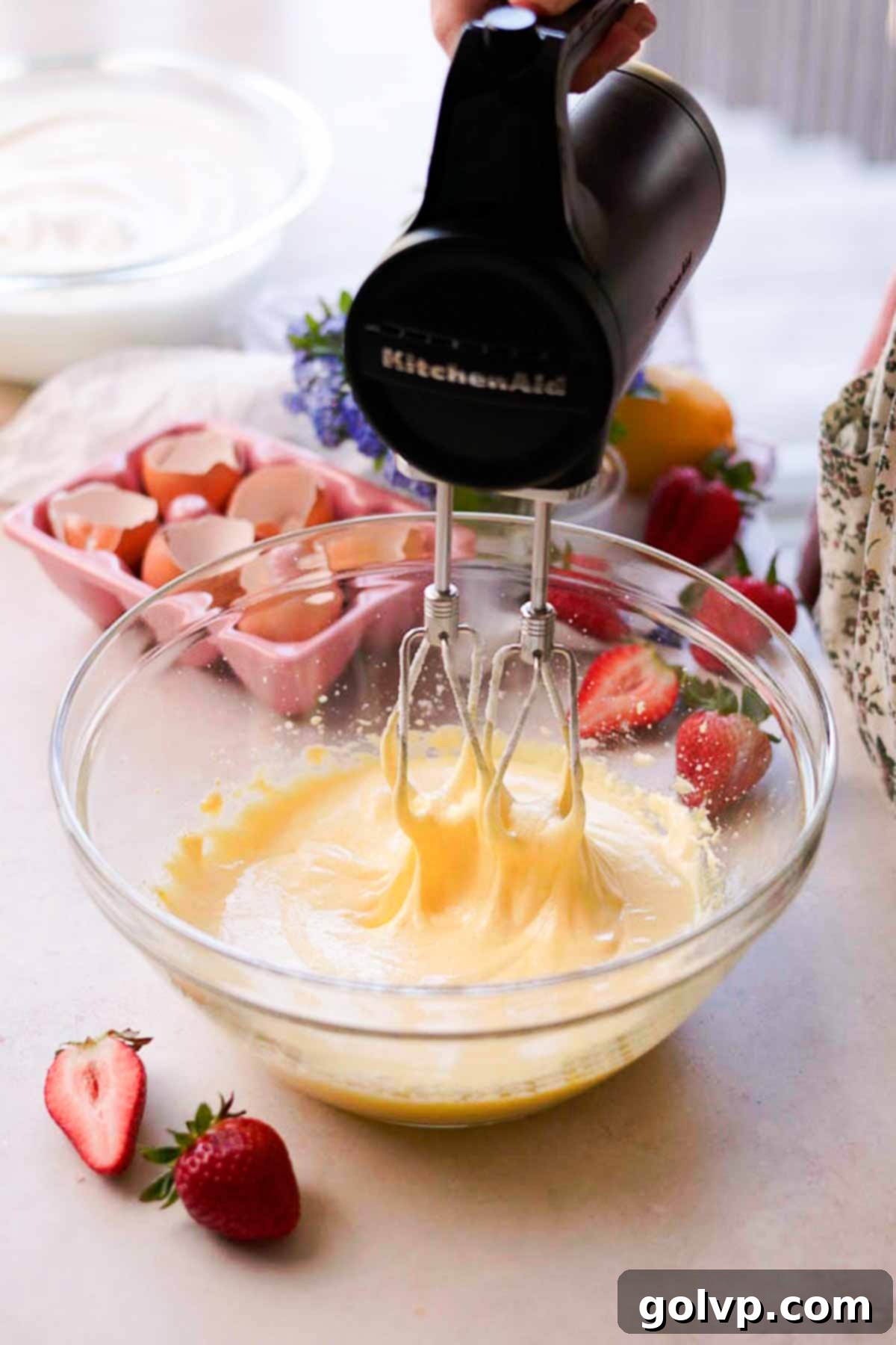 beating egg yolks and sugar with an electric mixer in a glass bowl
