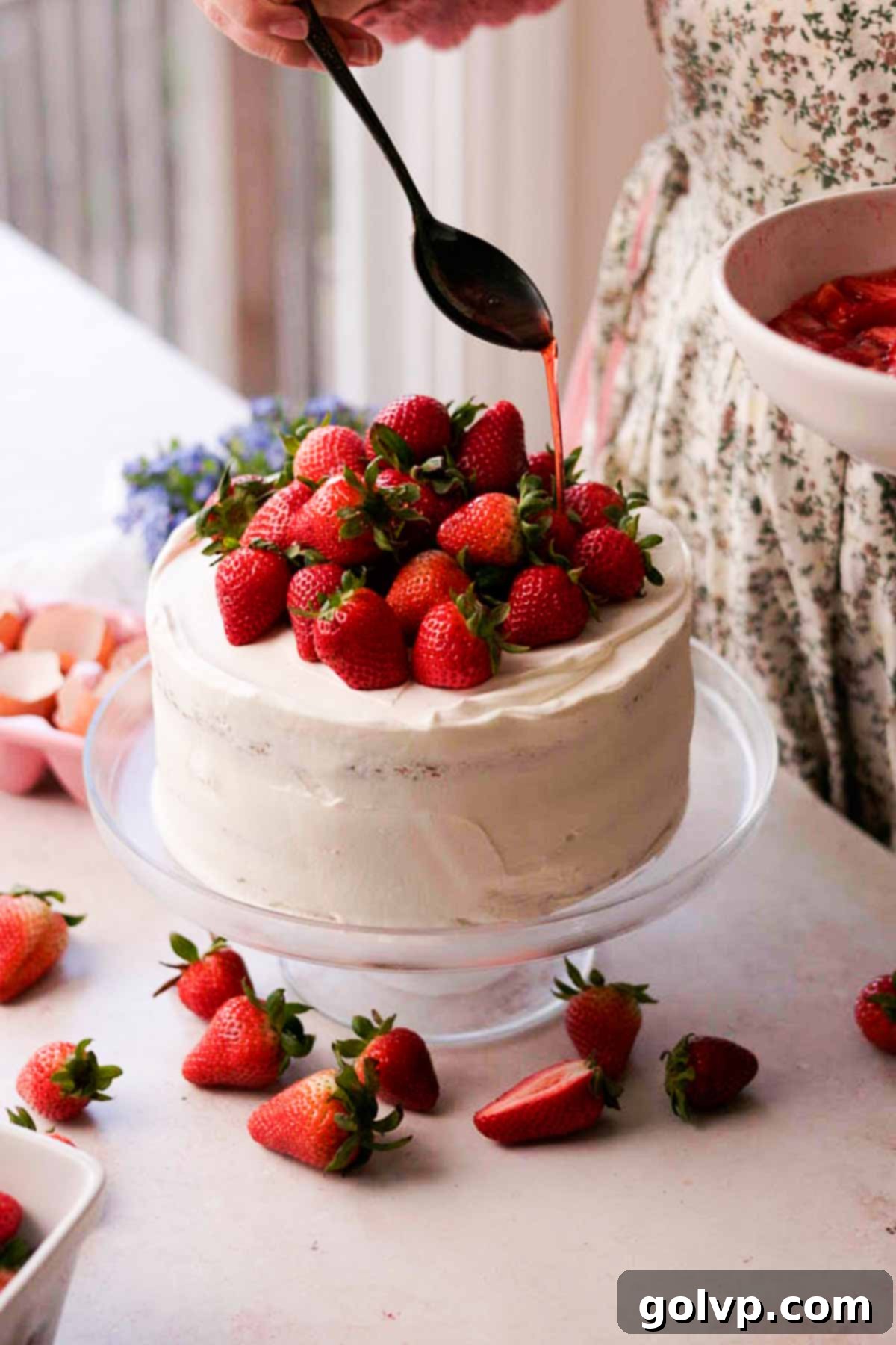 drizzling strawberry syrup over top of layered strawberry chiffon cake