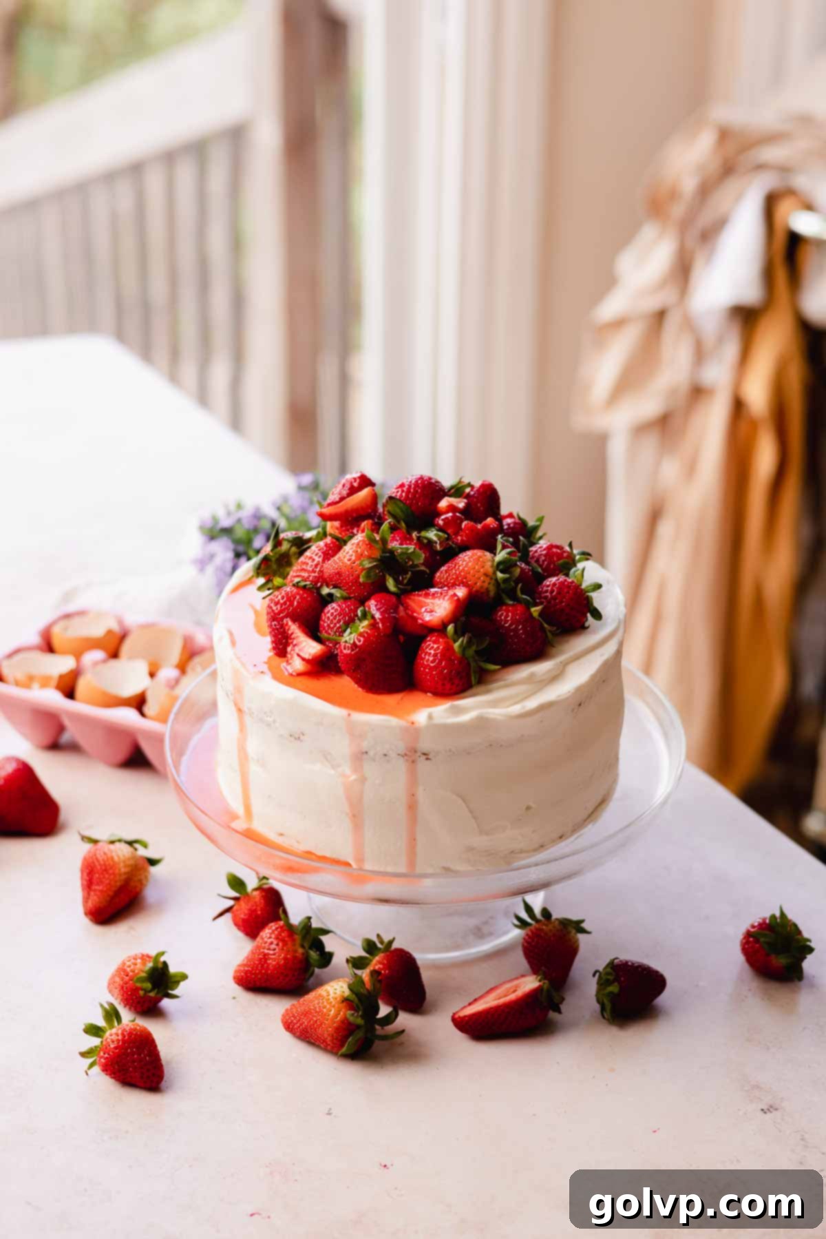 layered cake frosted with white frosting and topped with fresh strawberries
