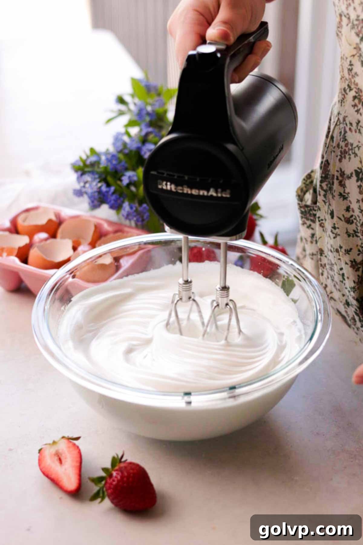 whipping egg whites in a large glass bowl with electric mixer