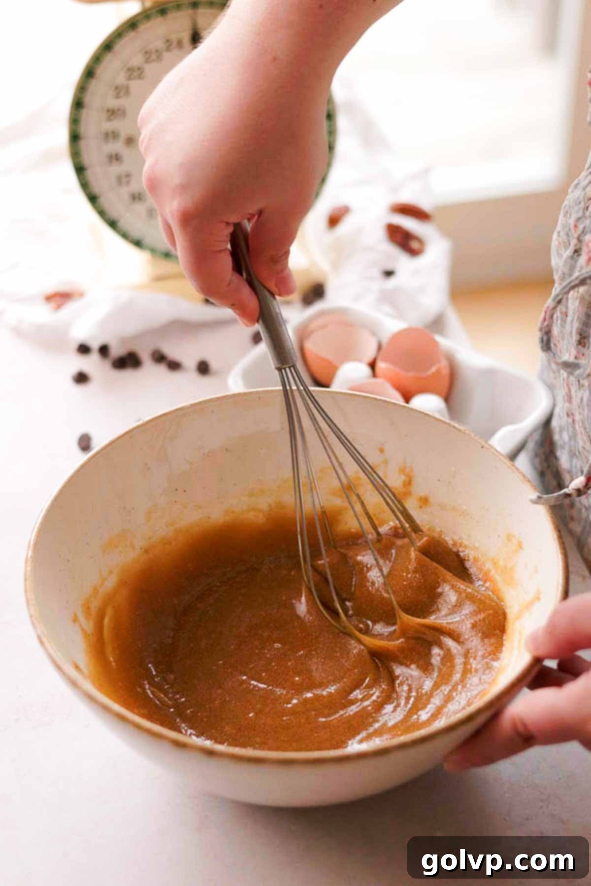 pecan topping ingredients whisked into a gooey light brown mix in a glass bowl