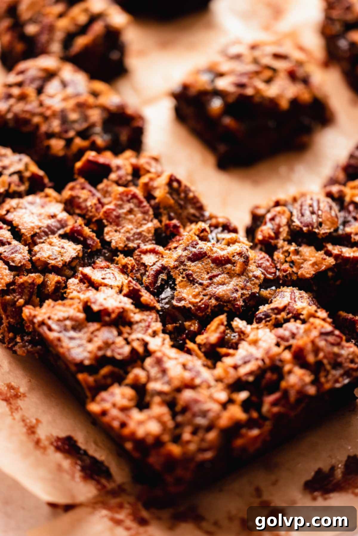 brownies cut in perfect squares with a pecan crusted top, arranged on a white surface