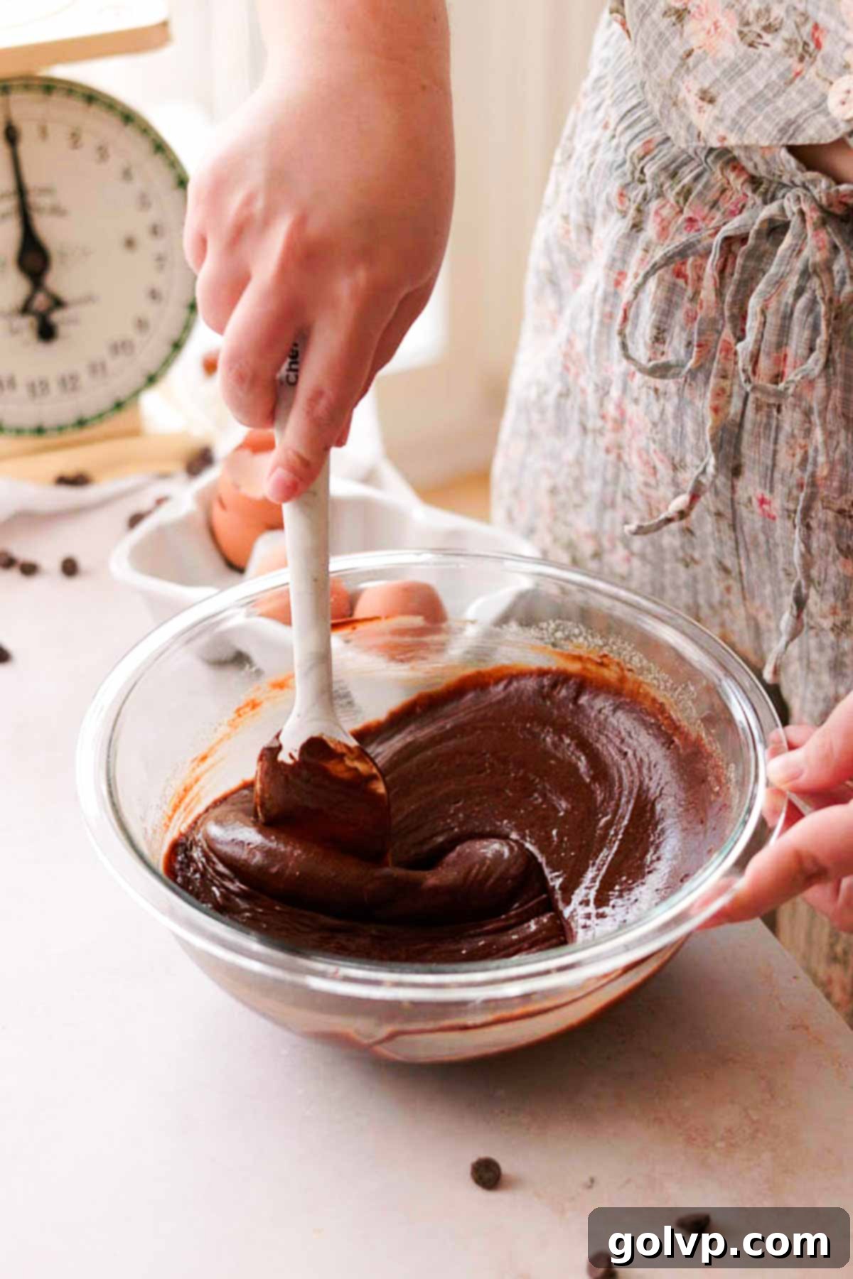 stirring the cooled melted chocolate and butter mixture into the egg and sugar mixture with a spatula in a glass bowl