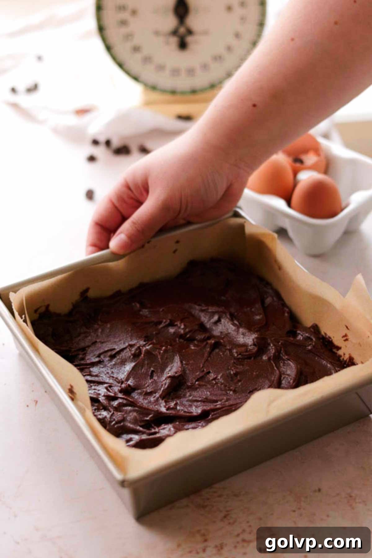 spread brownie batter evenly in a square tin pan lined with parchment paper