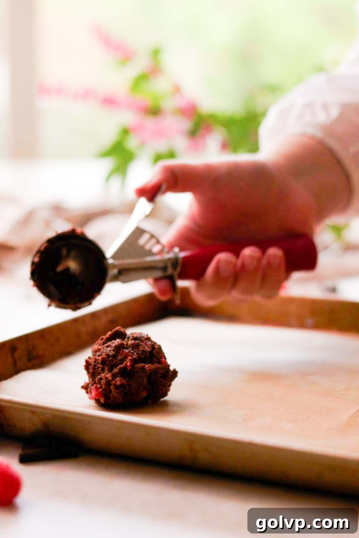 placing the first scoop of cookie dough onto a baking tray