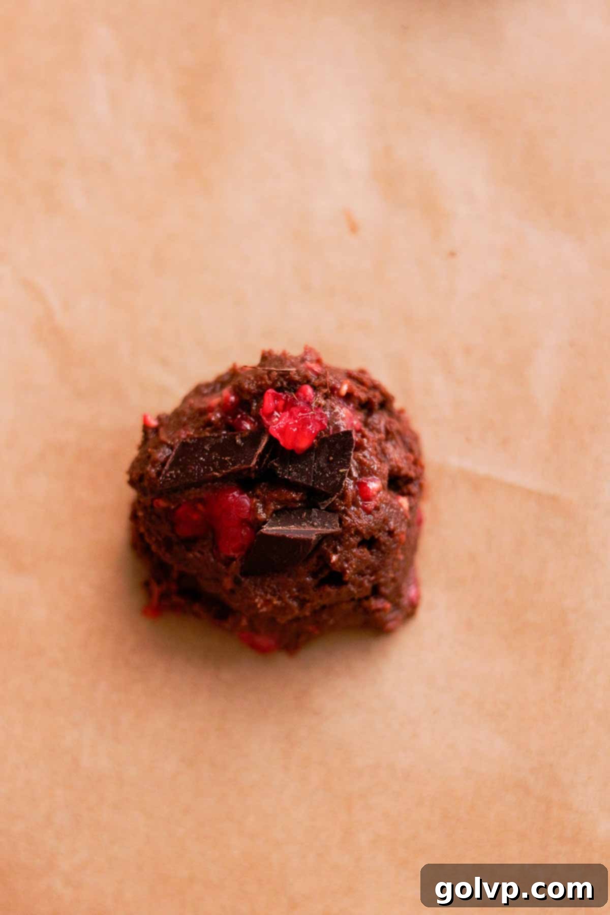 a scoop of cookie dough with bits of chocolate and fresh raspberries