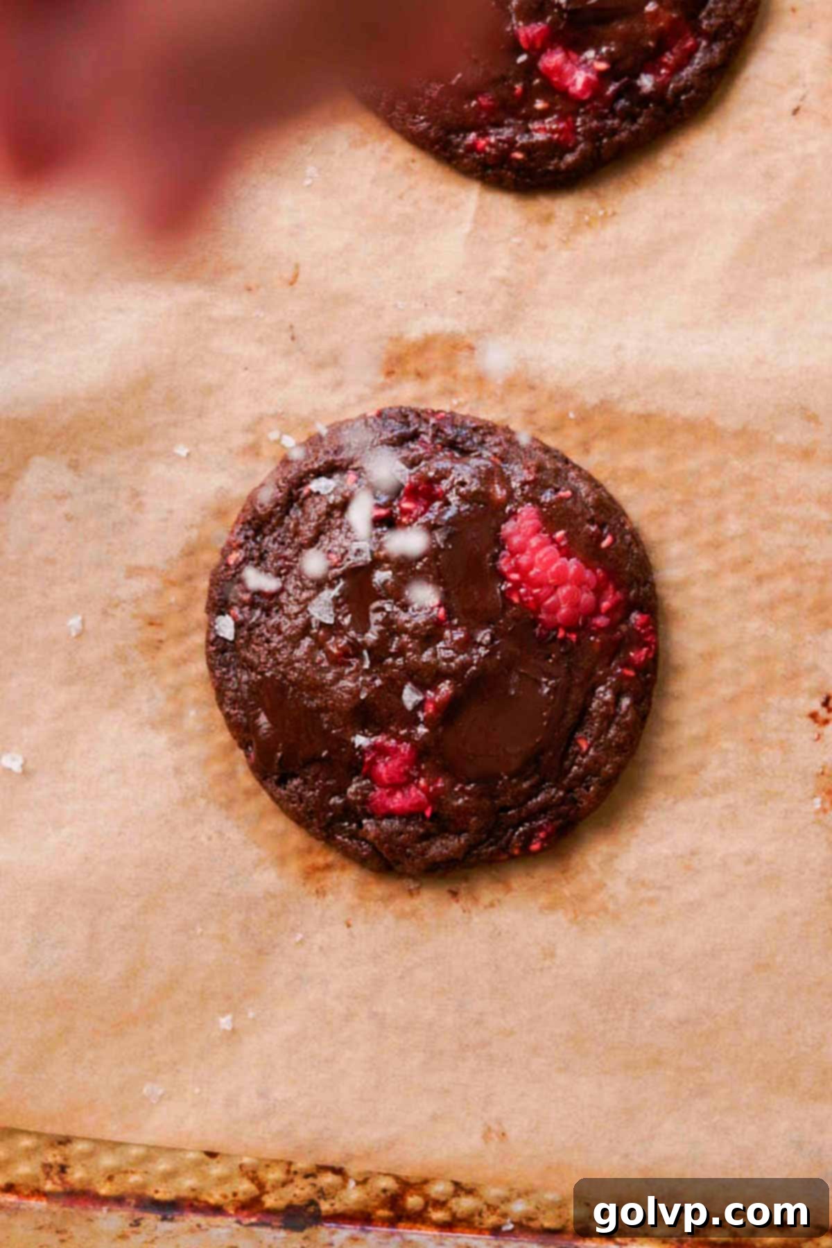 sprinkling flaky salt on raspberry chocolate cookie