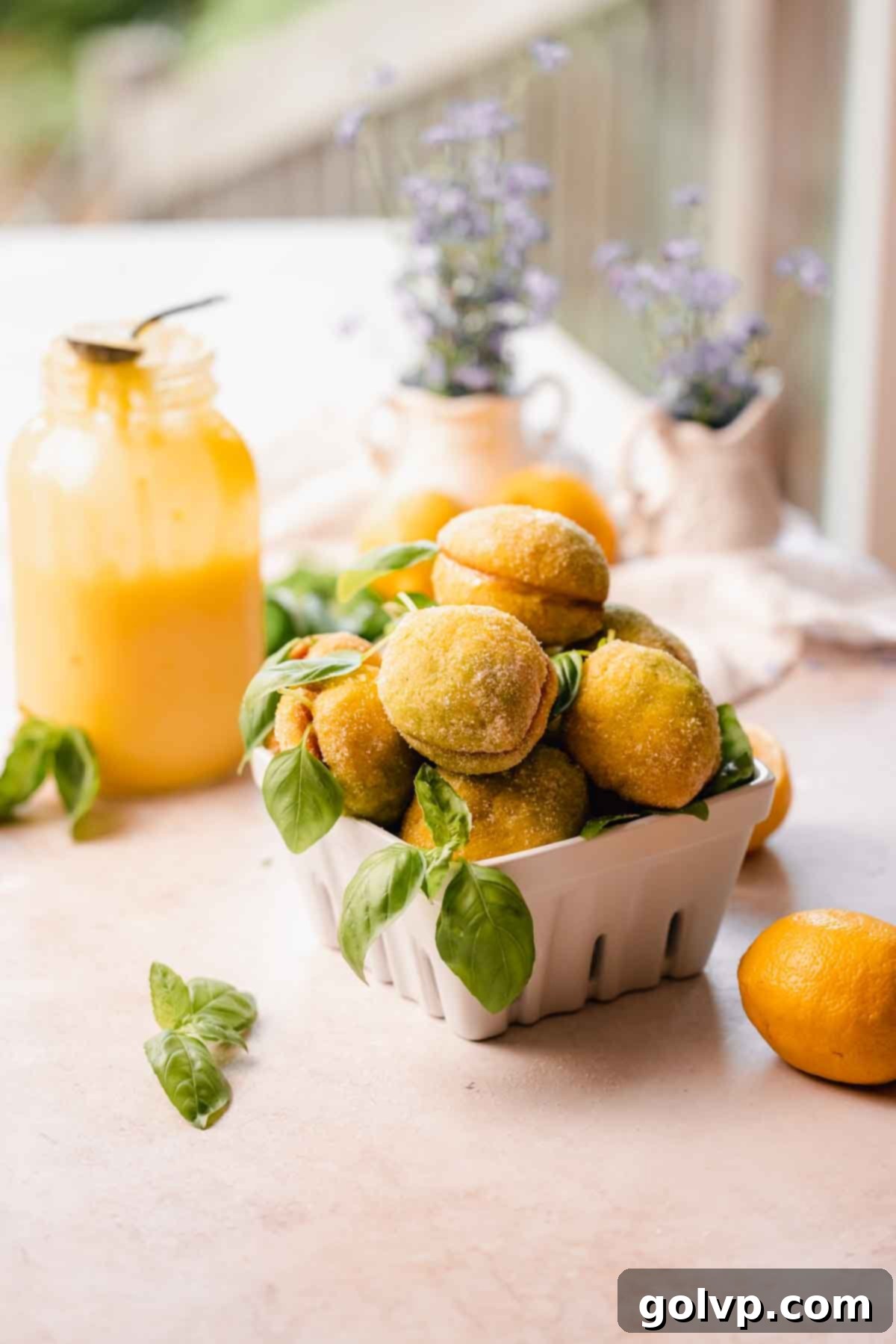 A bowl filled with vibrant, sugar-coated Italian lemon olive oil cookies, each adorned with a fresh basil leaf, showcasing their delightful lemon shape and inviting texture.