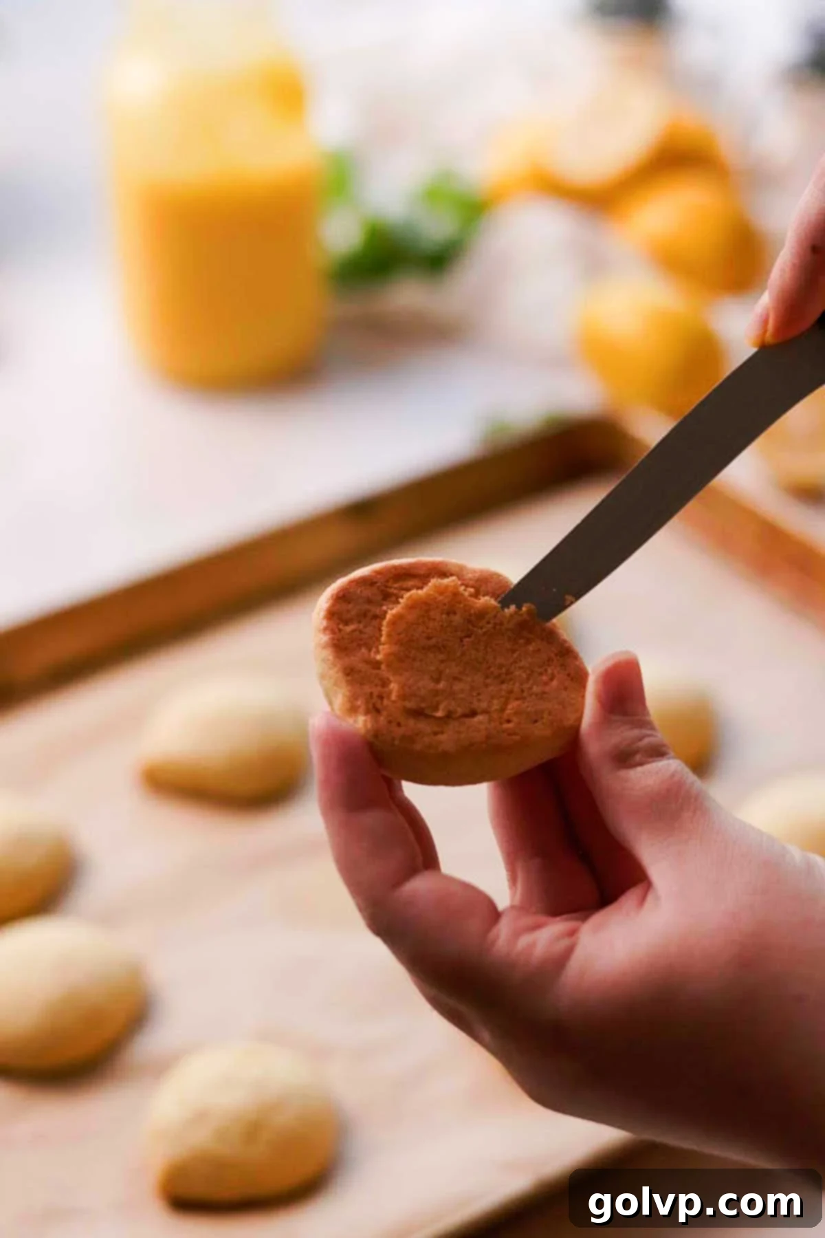 A small knife carefully cuts out the center of a warm Italian lemon cookie, creating a hollow for the lemon curd filling.