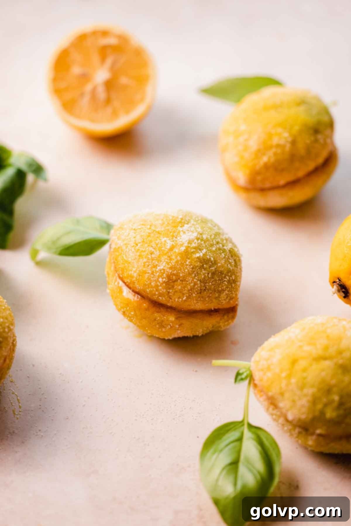 A stunning display of Italian wedding lemon cookies, each perfectly shaped, sugar-coated, and adorned with a fresh basil leaf, arranged beautifully in a bowl.