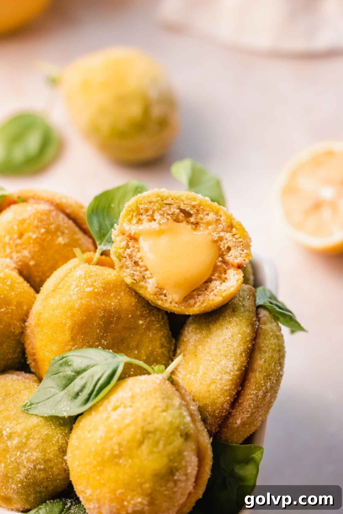 An Italian lemon cookie elegantly split in half, showcasing its generous, luscious lemon curd filling gently oozing from the center, highlighting its irresistible texture.