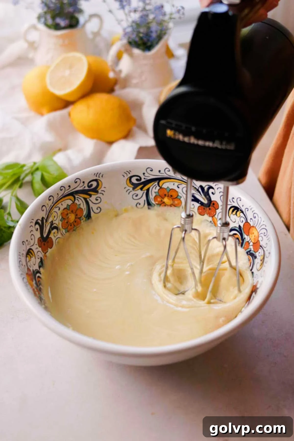 Electric whisk mixing olive oil, milk, vanilla extract, and salt into the lightened egg and sugar mixture in a bowl.