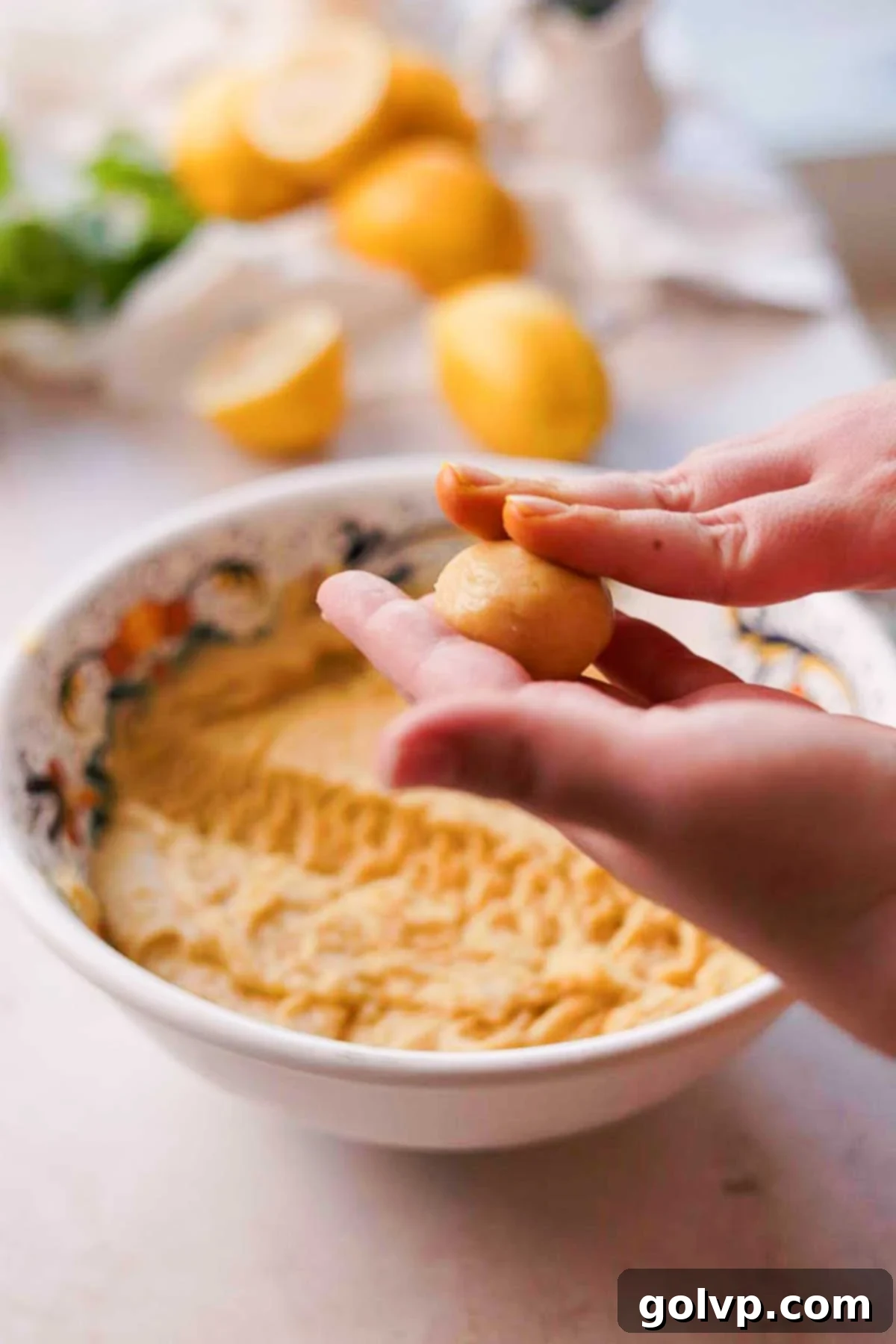 Hands gently rolling the portioned Italian lemon cookie dough into smooth, round balls, preparing them for shaping.
