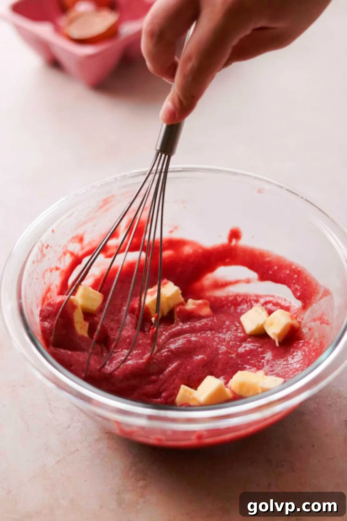 stirring cubes of butter into cherry curd with a whisk