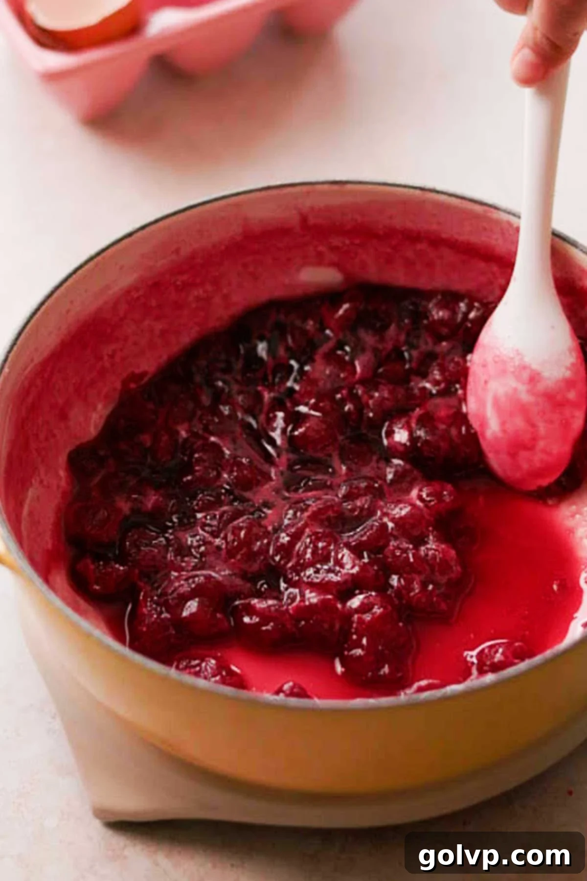 stirring simmering cherries down in saucepan