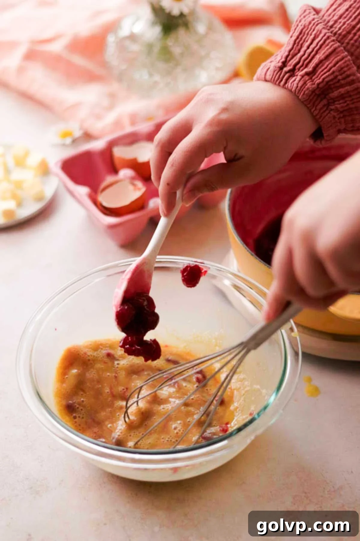 adding hot cherry sauce into eggs gradually and whisking with balloon whisk
