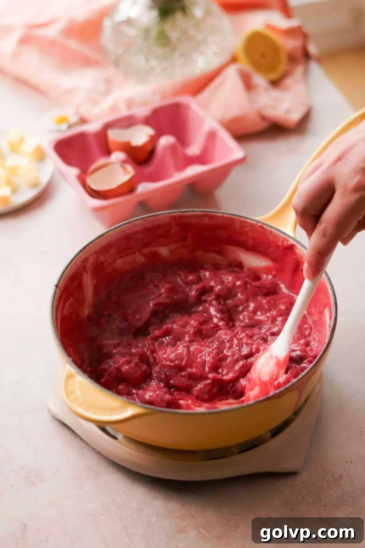 stirring thick and chunky cooked cherry curd in saucepan