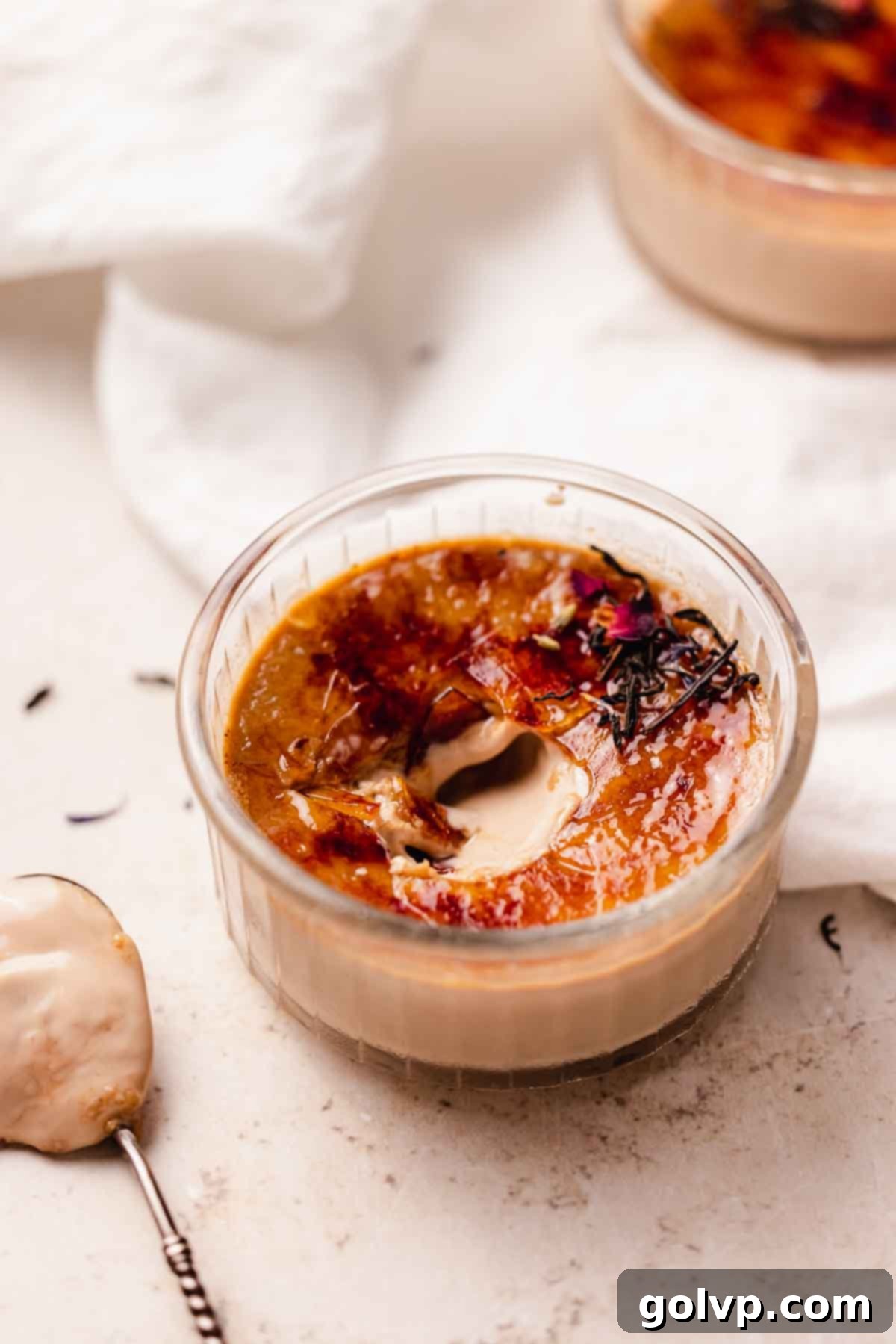 Elegantly presented Earl Grey Crème Brûlée with a perfect caramelized sugar crust and a spoon breaking through.
