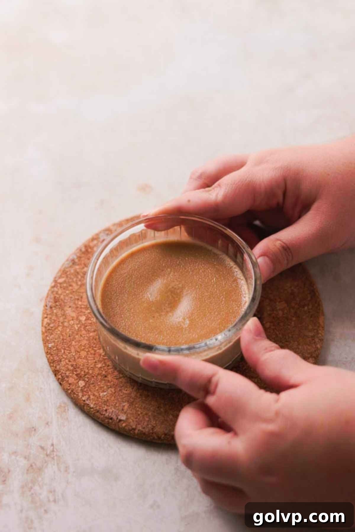 Baked crème brûlée ramekins in a water bath, cooling on a rack
