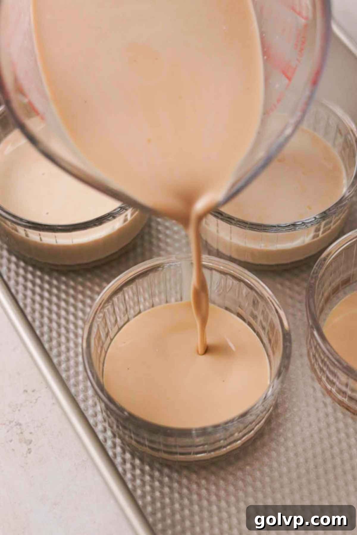 Custard mixture being poured into ramekins