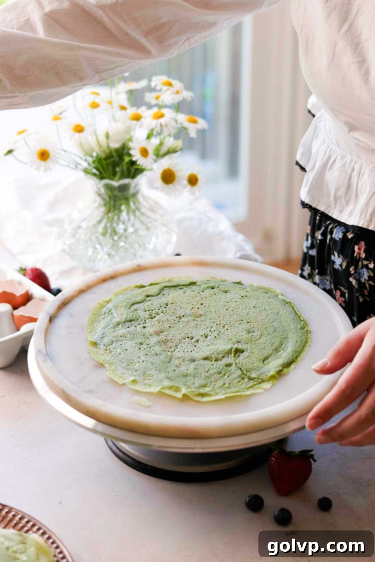 placing the first matcha cake crepe on a plate