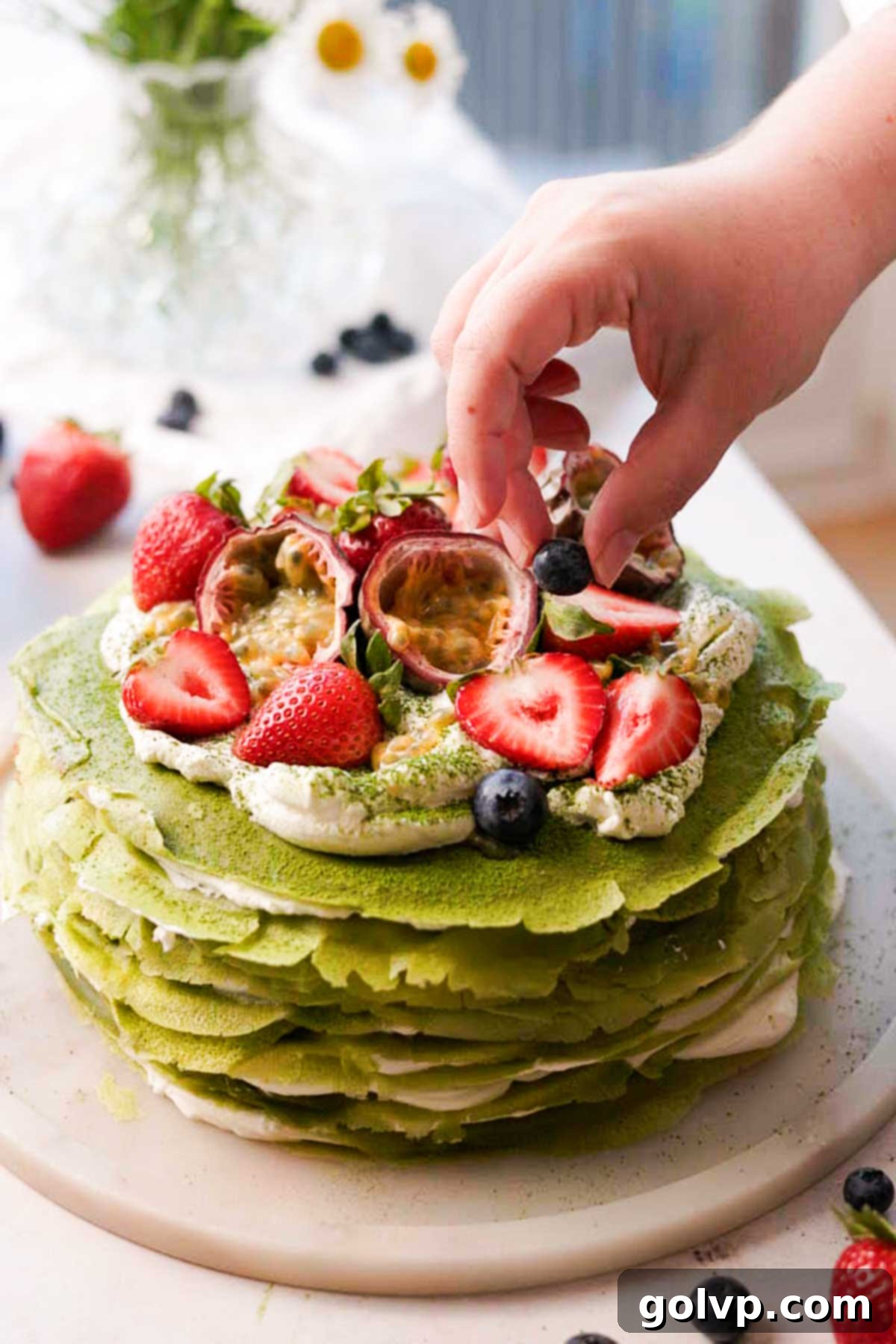 decorating the matcha crepe cake with strawberries, blueberries and passion fruit