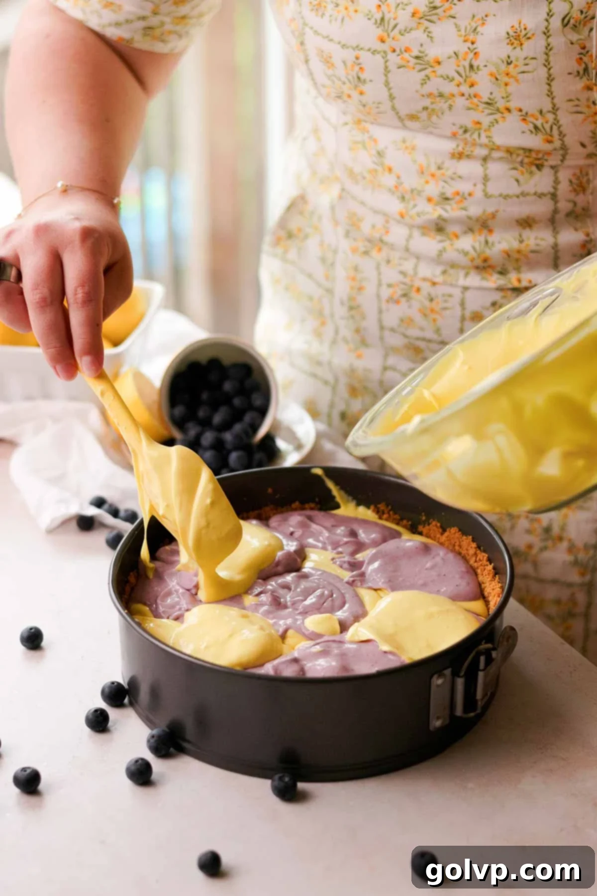 adding lemon cheesecake batter on top of blueberry batter