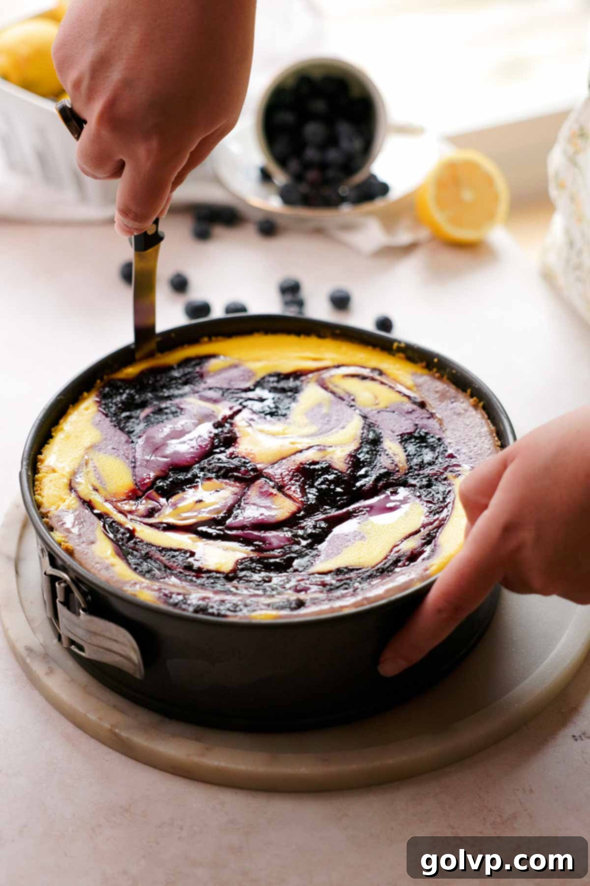 running a knife along the edge of the freshly baked cheesecake to separate it from the pan