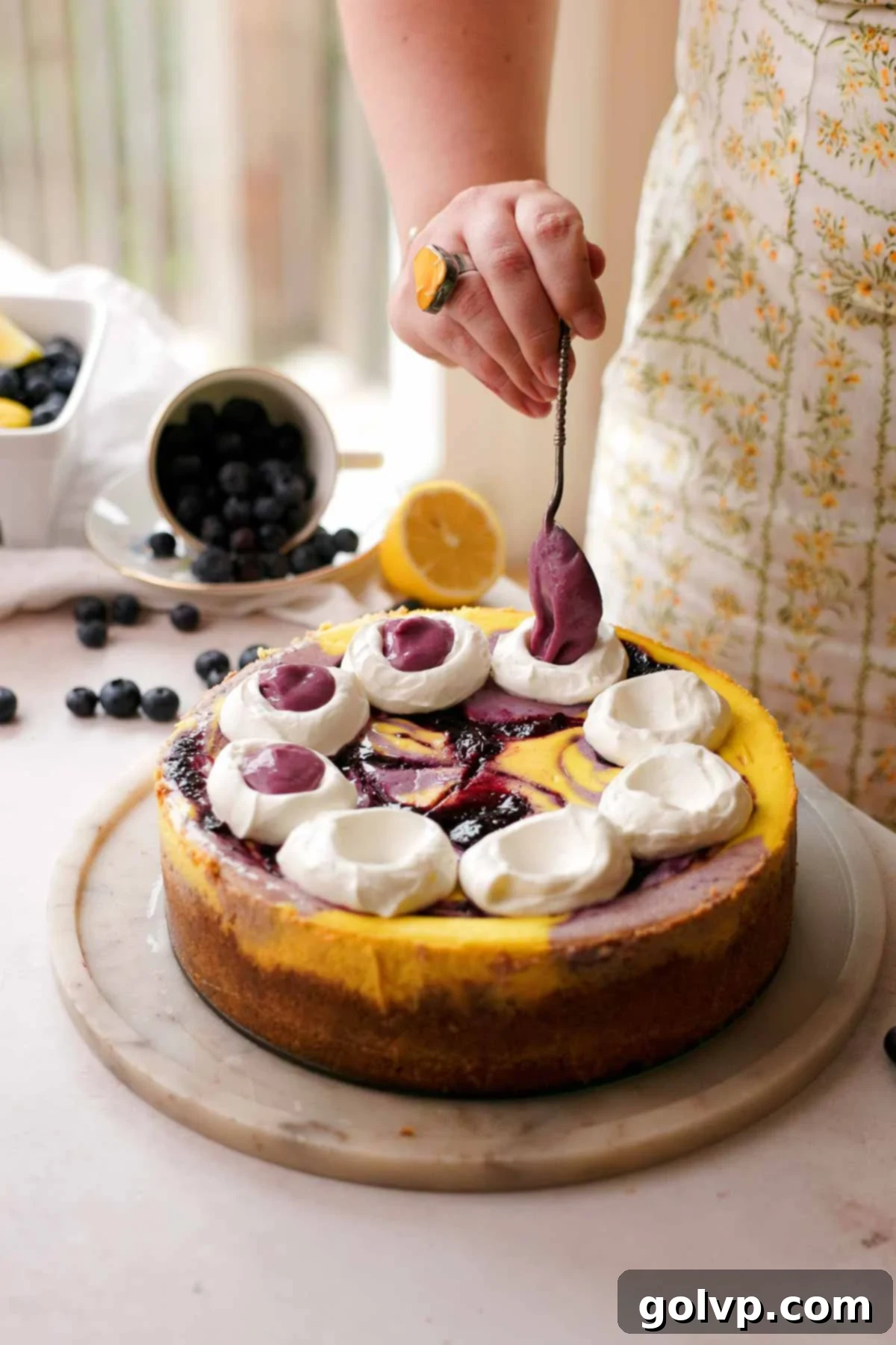 adding dollops on top of the blueberry lemon cheesecake