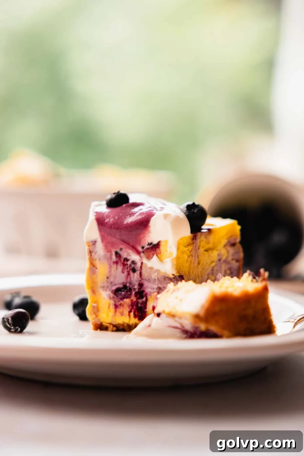 close up of a blueberry cheesecake slice with berries on top
