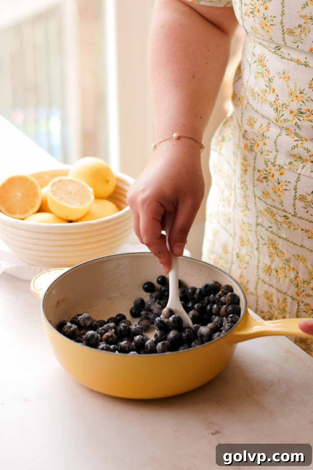 mixing blueberries with sugar and lemon juice in a saucepan