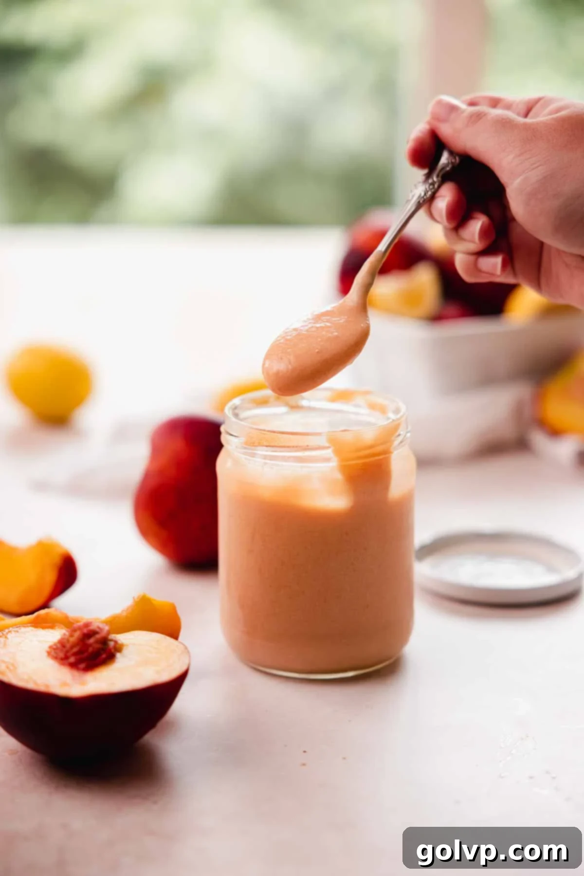 Close-up of vibrant homemade peach curd in a glass jar, showcasing its smooth texture and rich color