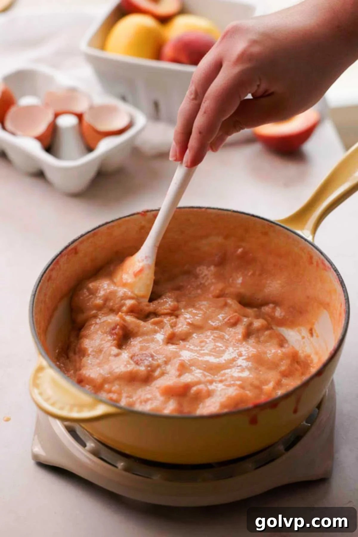 Cooking the combined peach and egg mixture in a saucepan, stirring constantly