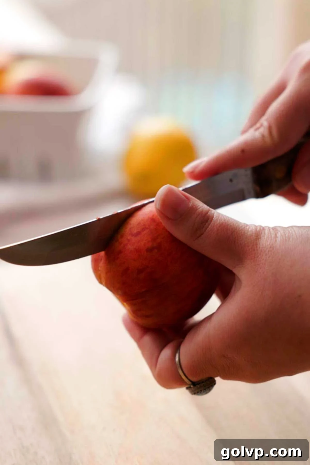 Cutting a fresh peach in half around its stone with a knife