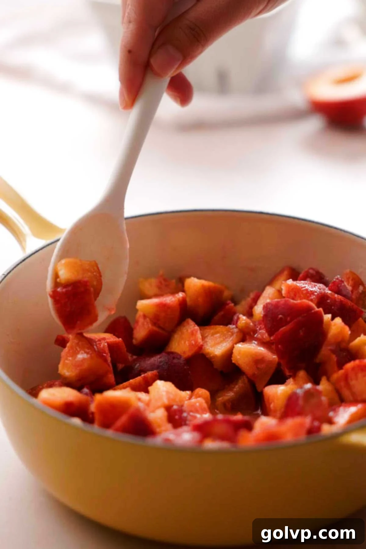 Stirring diced peaches, granulated sugar, and lemon juice in a saucepan over low heat
