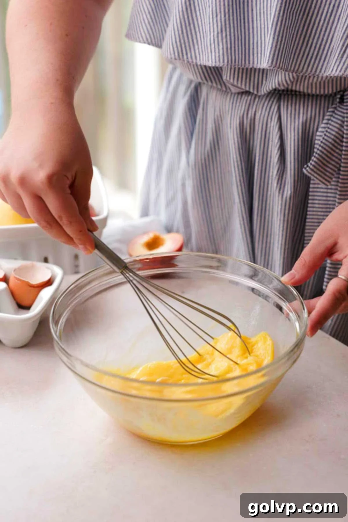 Whisking eggs smoothly by hand in a clear glass bowl