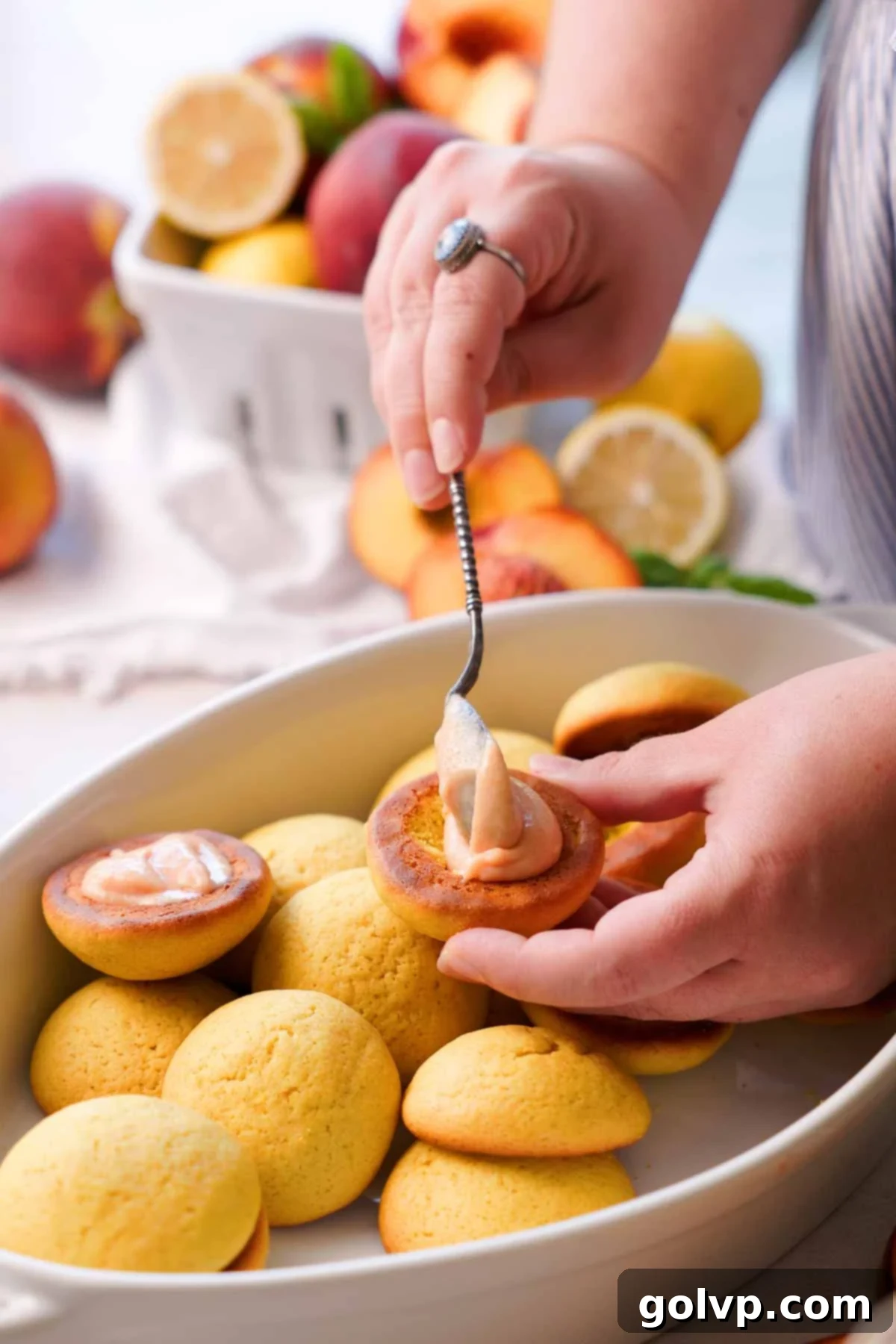 filling the middle of a peach cookie with a spoon full of peach curd