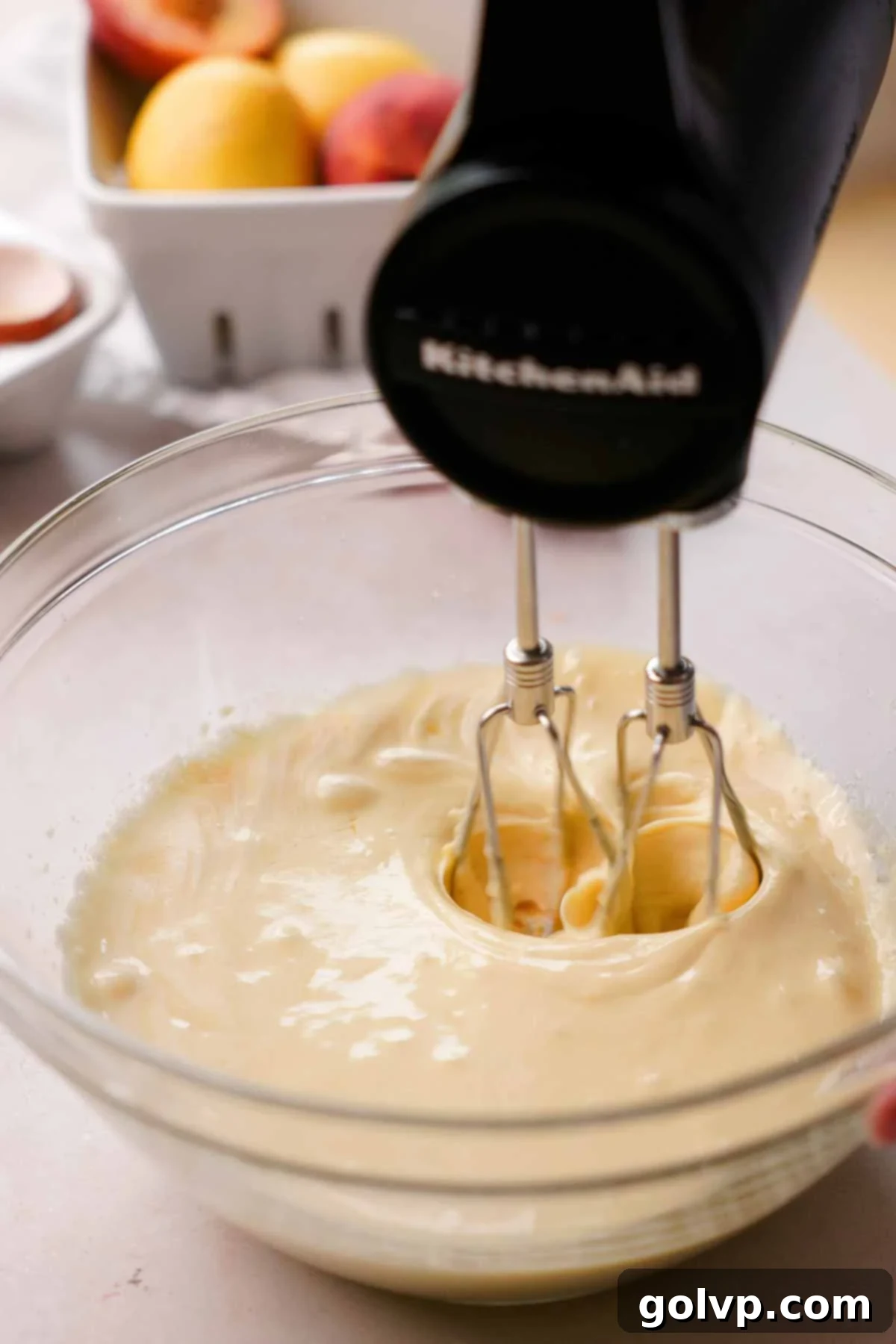 mixing the wet ingredients for the peach cookies in a glass bowl with an electric mixer