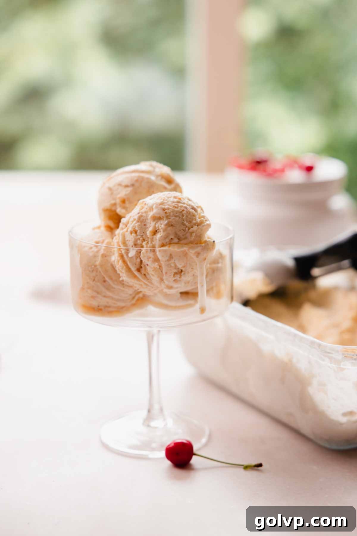 Close-up of creamy brown butter ice cream slowly melting in a clear glass, revealing vanilla bean specks.