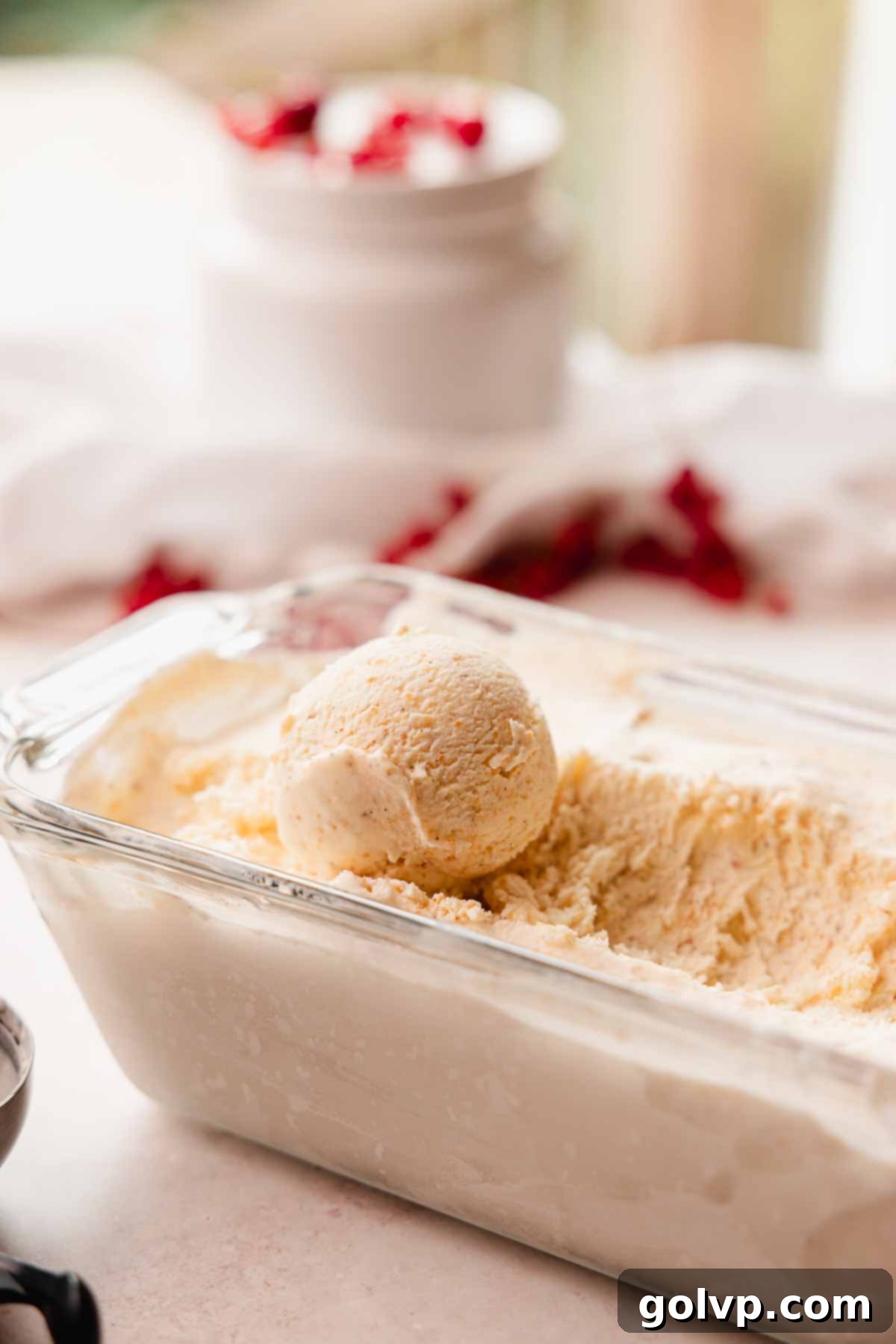 A scoop of rich vanilla brown butter ice cream sitting atop a tray filled with more ice cream.