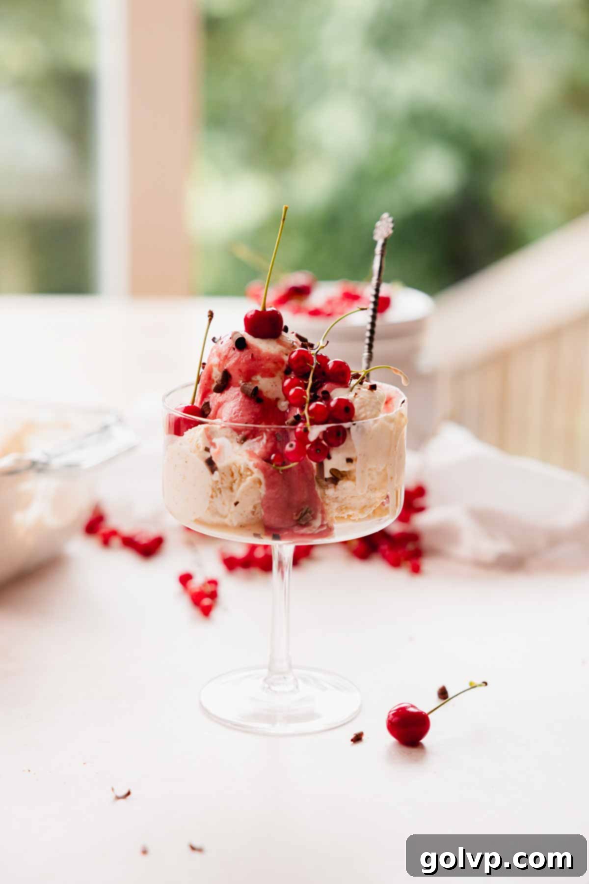 Brown butter ice cream in a glass topped with fresh cherries and red currants, ready to be enjoyed.