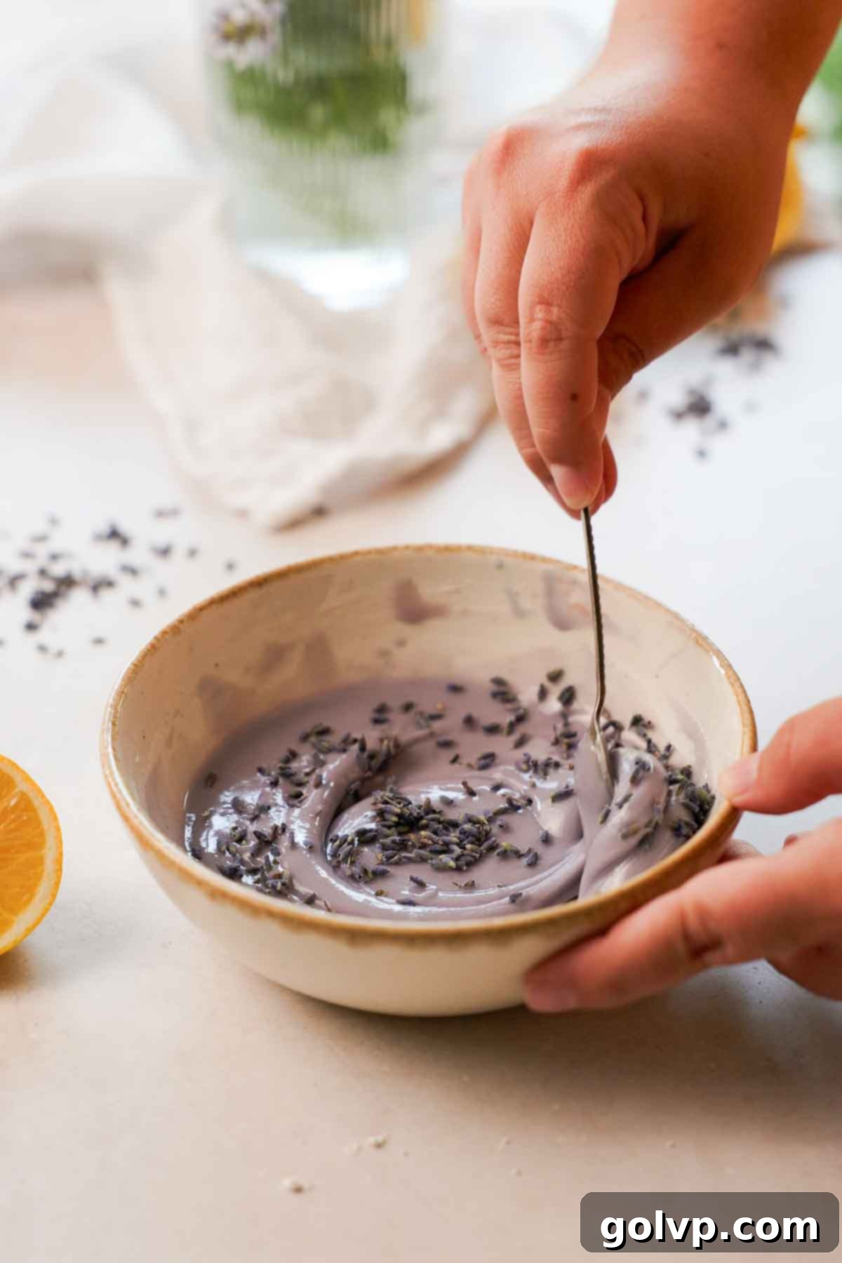 stirring purple lemon lavender glaze in a bowl with a spoon