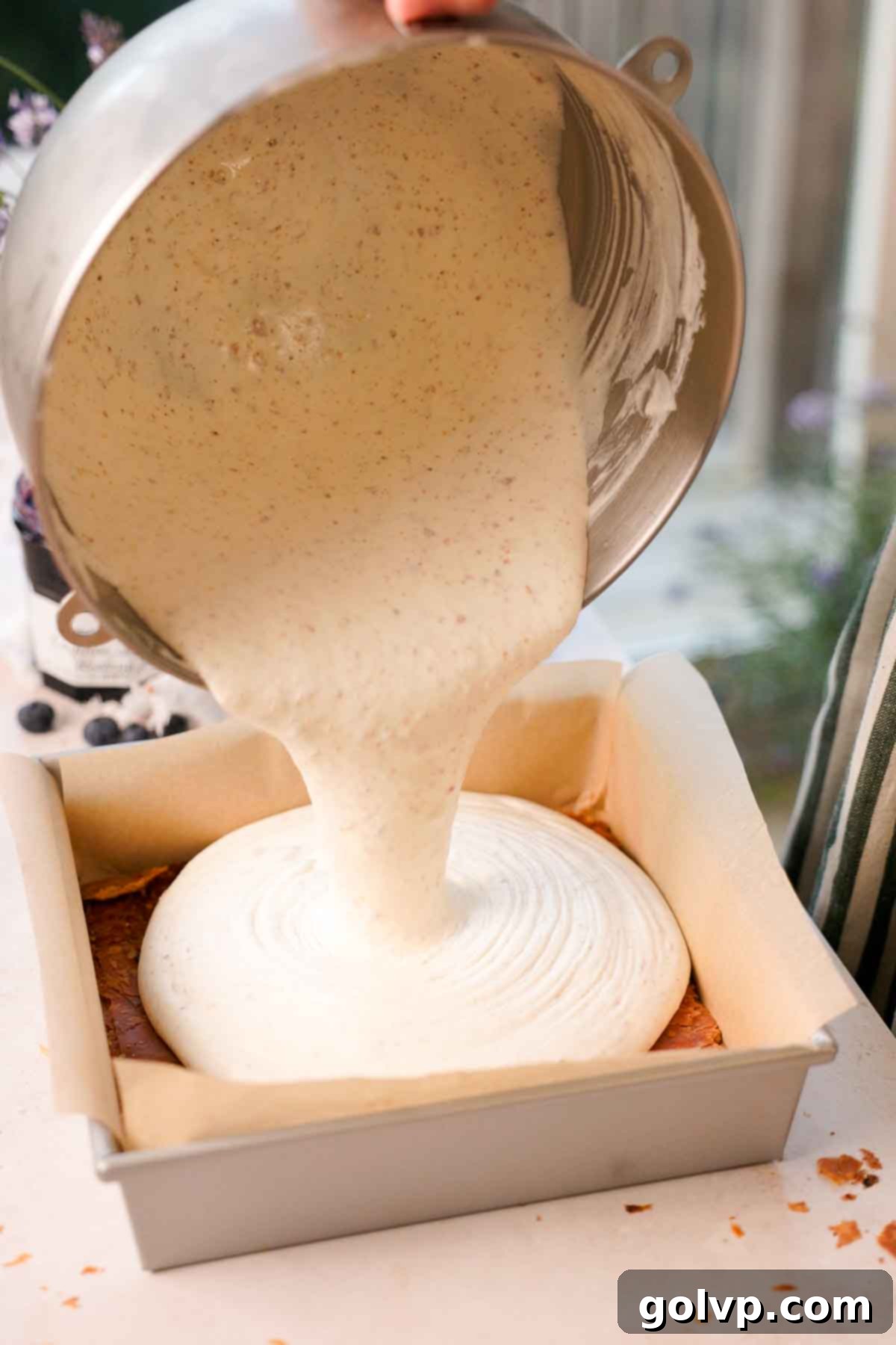 pouring no churn brown butter ice cream mixture into a parchment-lined baking pan