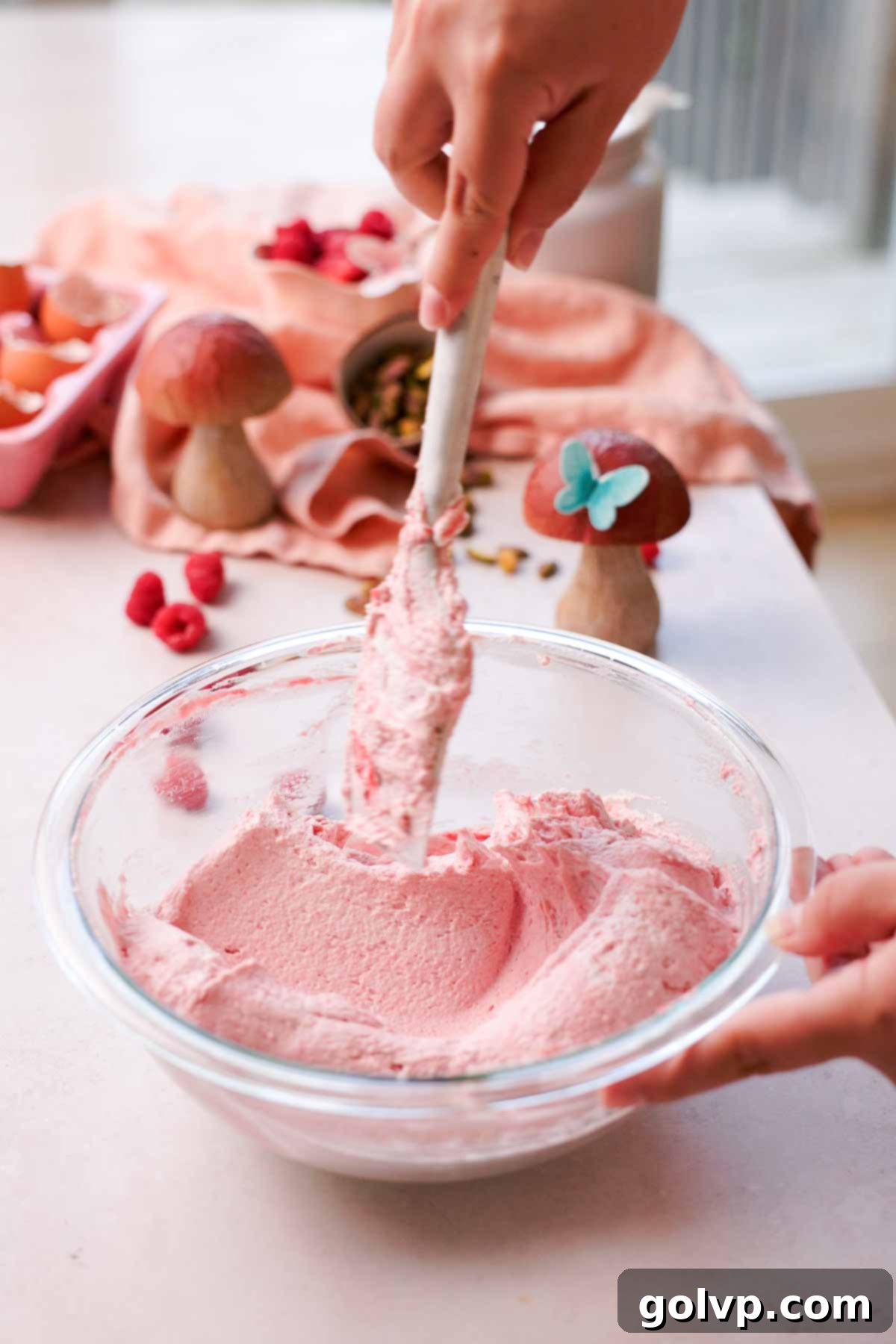 folding raspberry whipped cream with silicone whisk