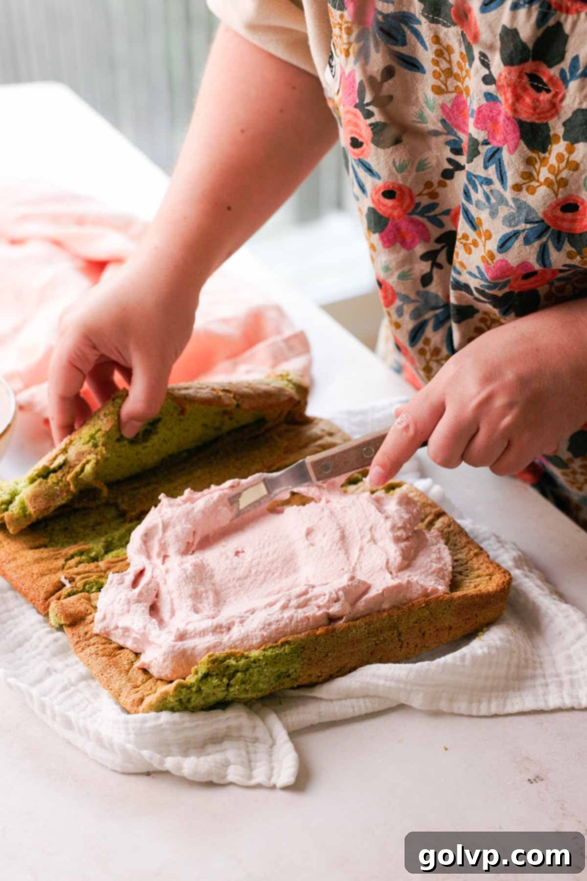 spreading raspberry mascarpone filling on pistachio cake
