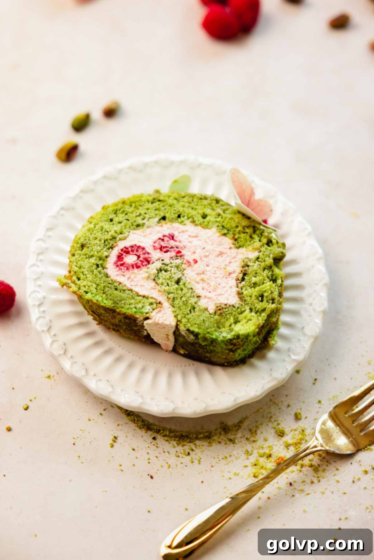slice of pistachio roll cake with raspberry filling on small white plate