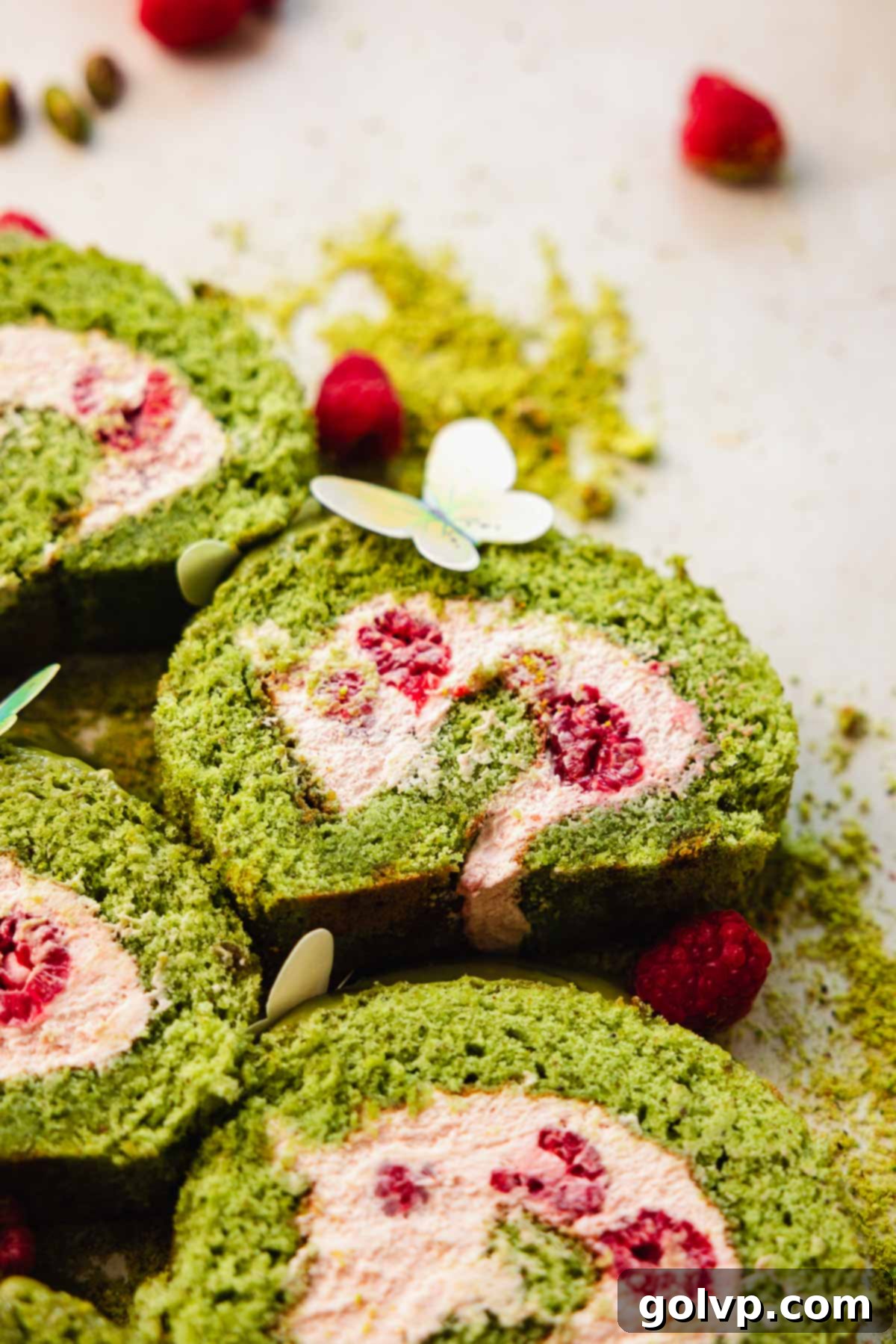 slices of pistachio cake roll with fresh raspberries inside filling