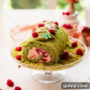 raspberry pistachio cake roll on cake plate with ground pistachios